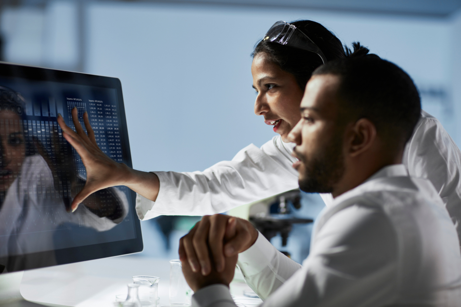 Two researchers discussing data displayed on computer screen