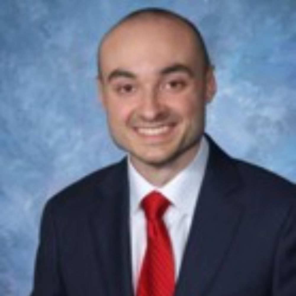 bald man wearing dark suit and red tie