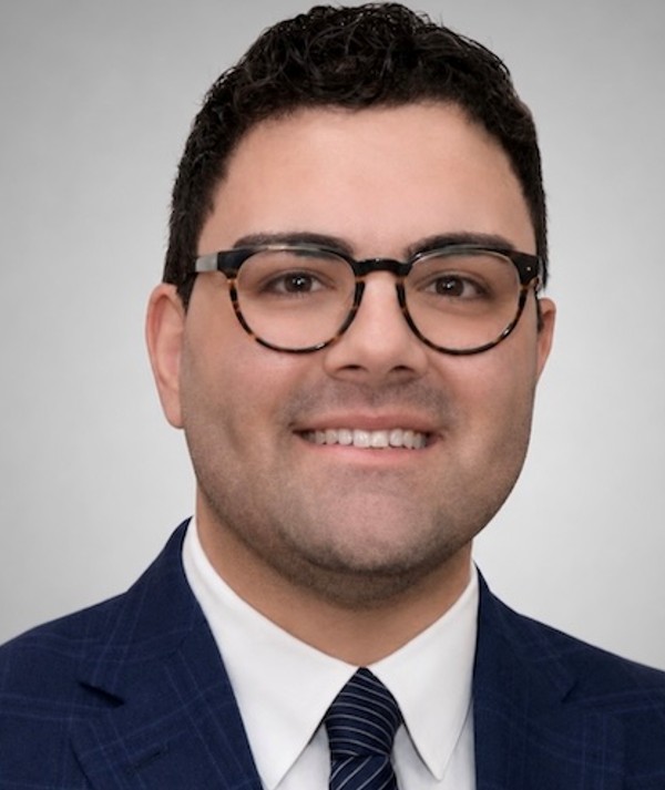 man with dark hair and glasses wearing suit