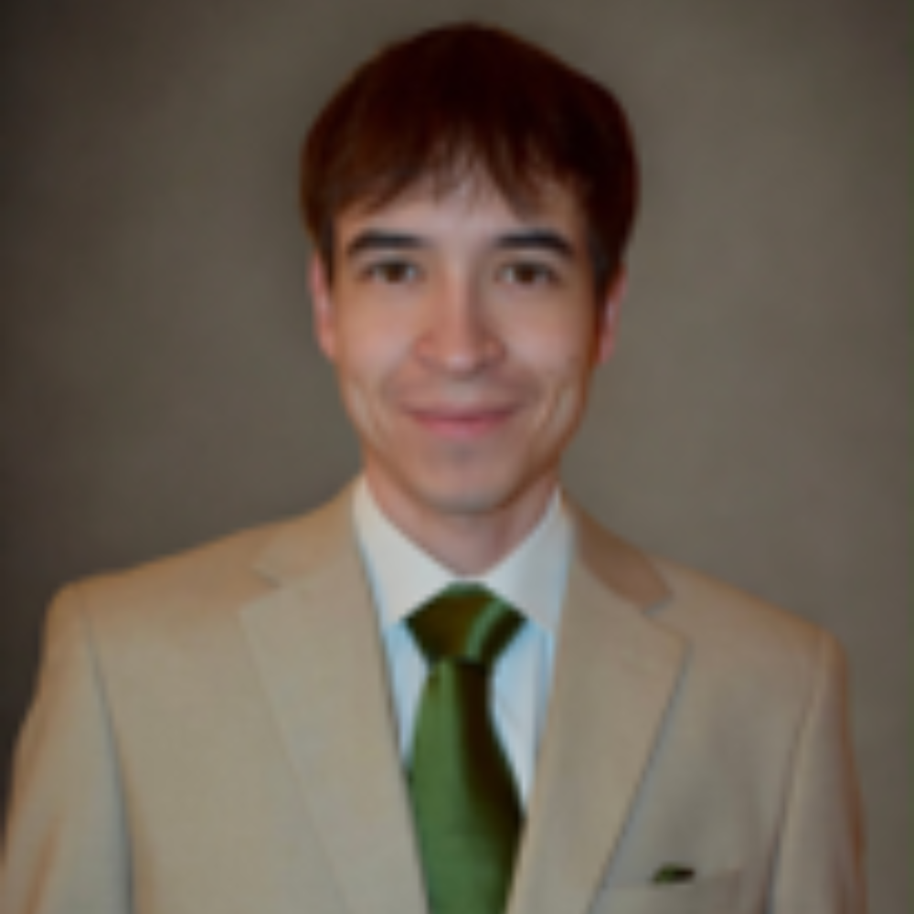 man with short dark hair wearing tan suit jacket and green tie