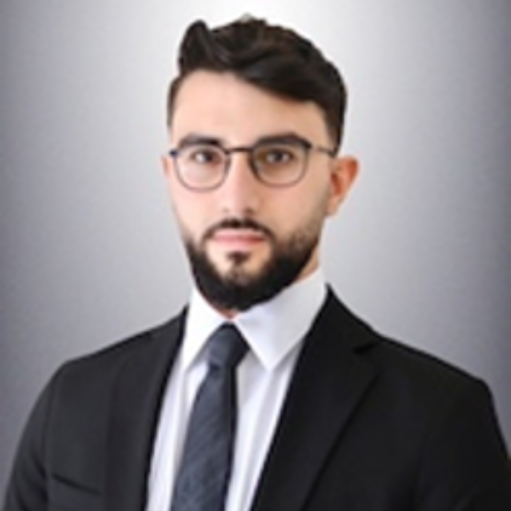 man with dark hair and glasses with mustache and beard wearing dark suit