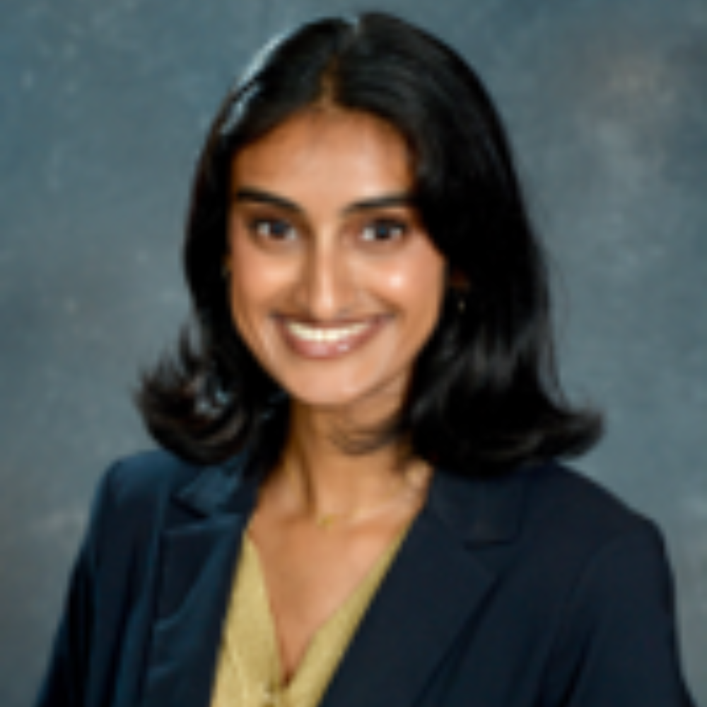 woman with dark hair wearing dark blazer and tan top
