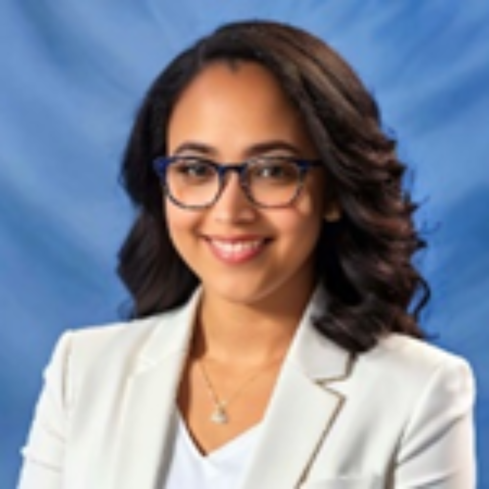 woman with long dark hair wearing glasses and white blazer and top