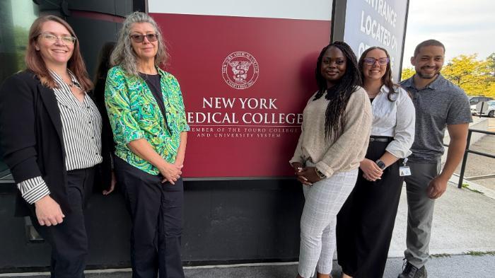 Team of people posed against NYMC sign