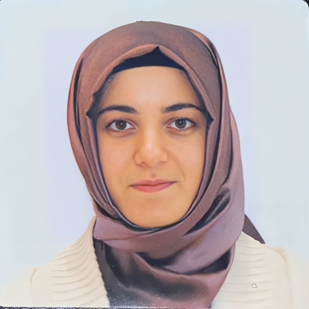 woman wearing purple head scarf in front of light gray background
