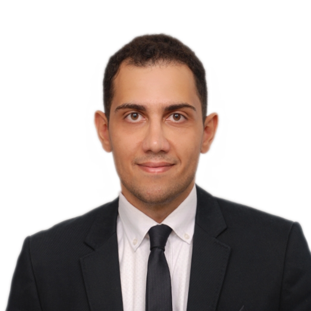 man with dark hair wearing black suit and tie in front of white background