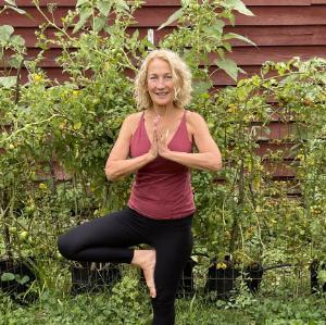 Mary Butler Fink in front of shrub doing a yoga pose