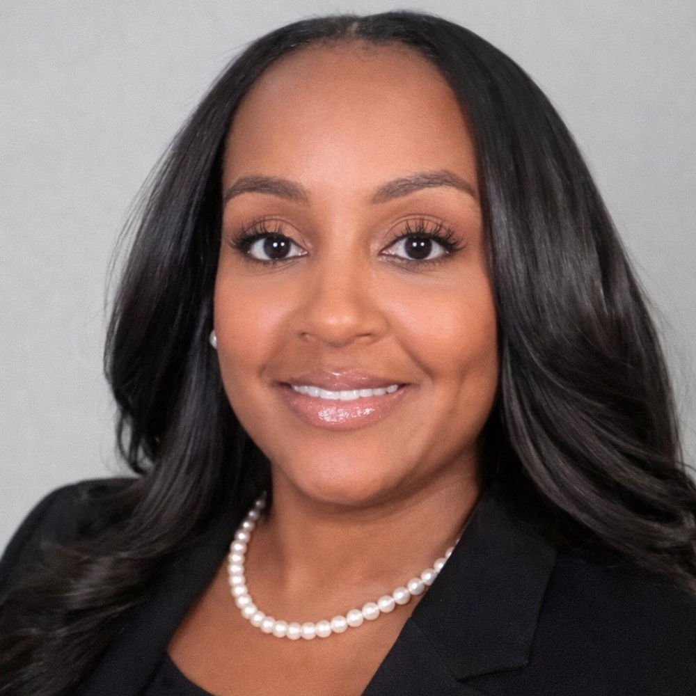 woman with dark skin and black hair wearing black dress in front of white background