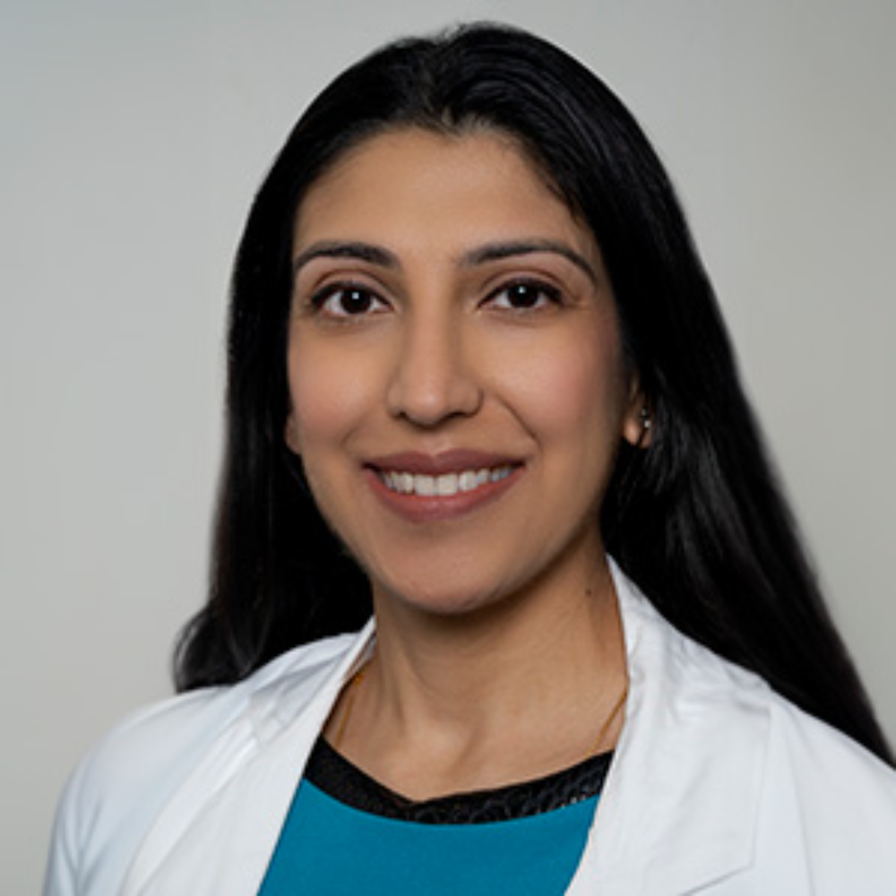 woman with long dark hair wearing white coat and blue top