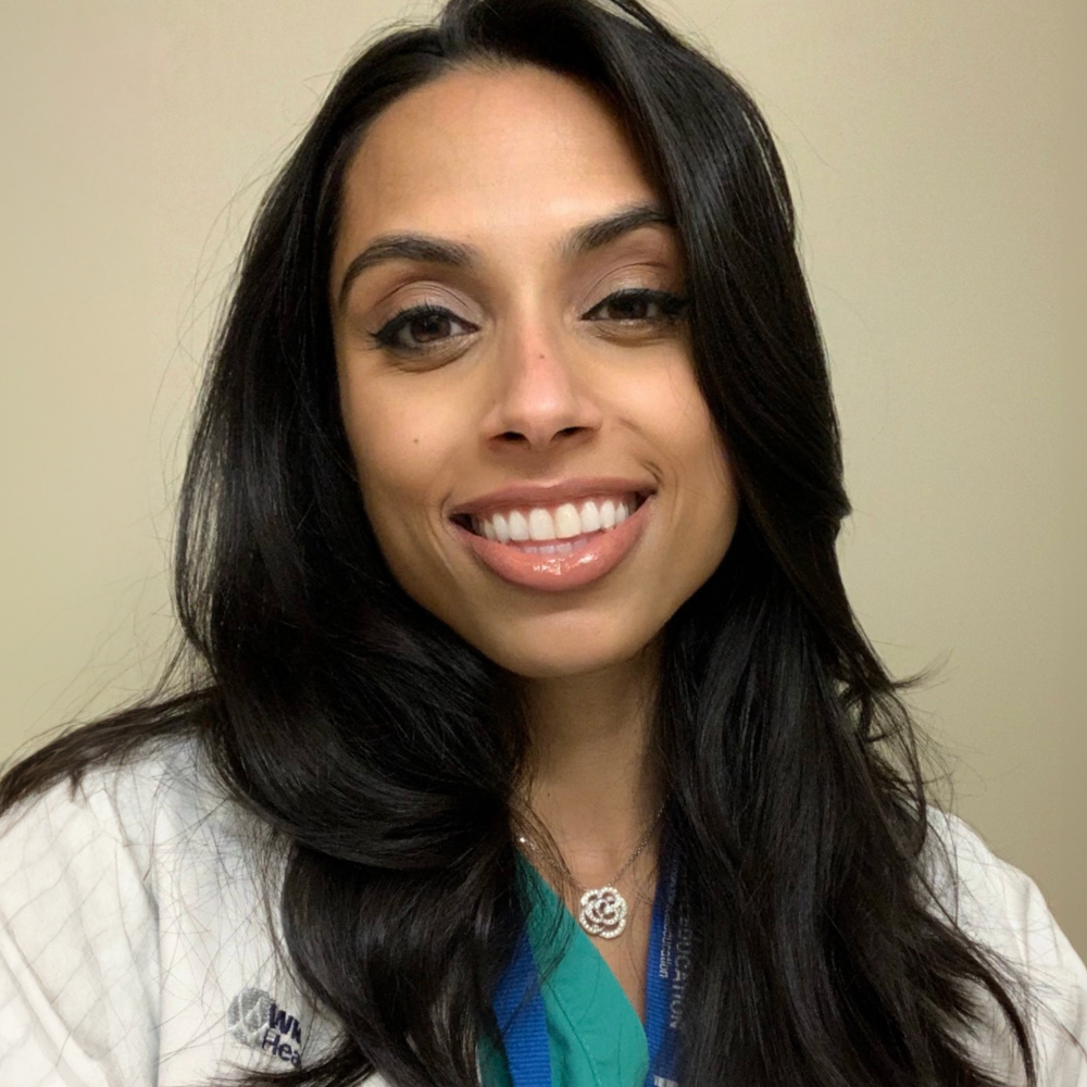 woman with long dark hair wearing white coat and scrubs
