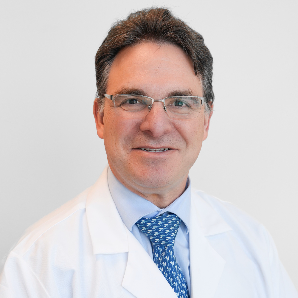 man with glasses and dark hair wearing white coat