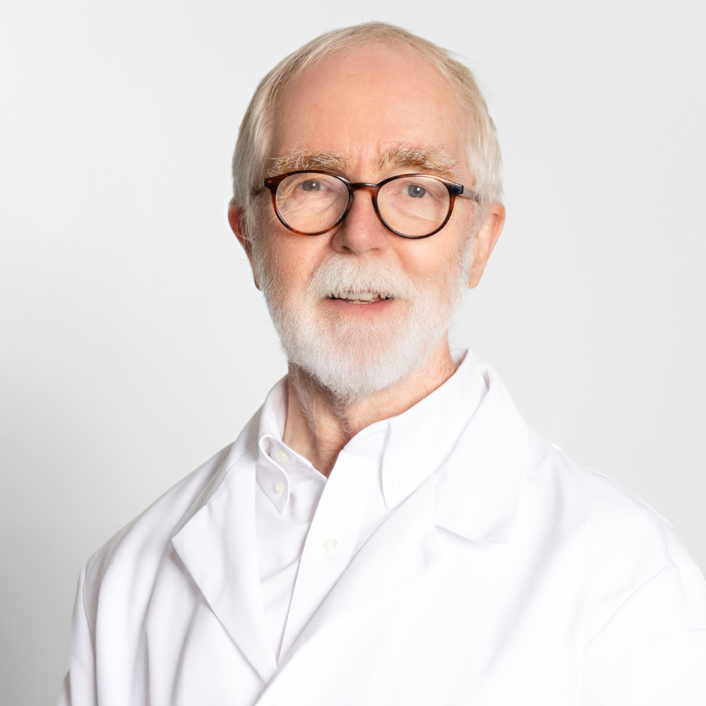man with white hair and beard wearing glasses with white coat