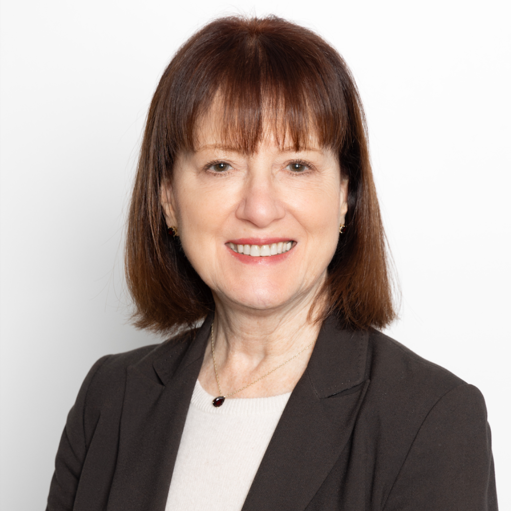 woman with brown hair wearing brown blazer and cream top