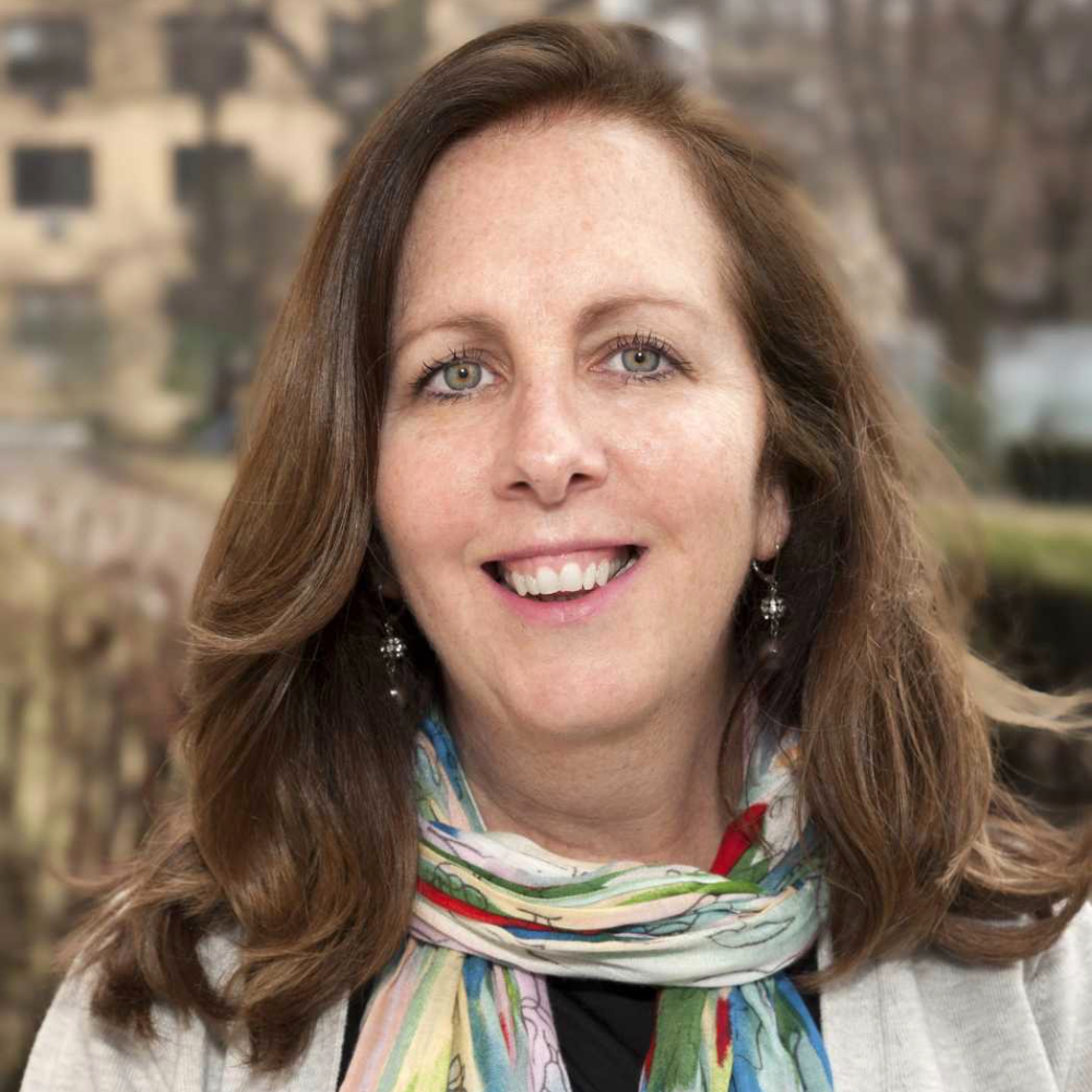 woman with brown hair wearing scarf and tan jacket