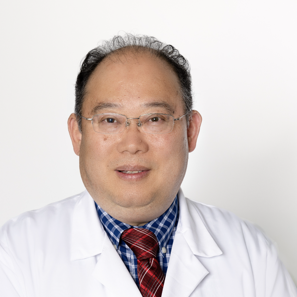 Asian man with glasses wearing white coat, blue checkered shirt