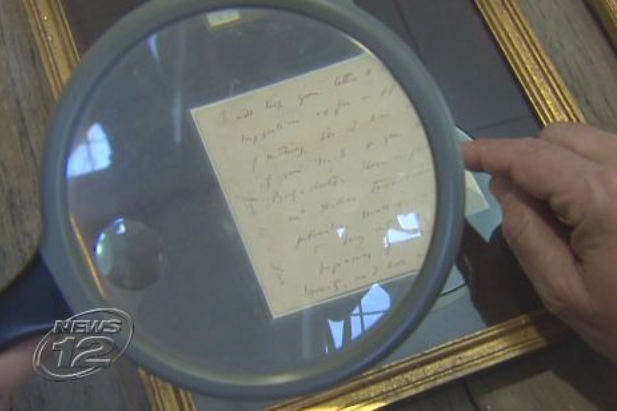 Screenshot from the News of a magnifying glass hovering the letter in cursive writing