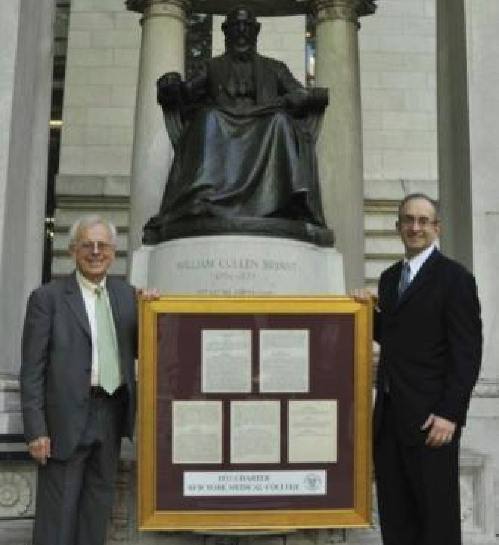 Karl Adler, M.D., then-NYMC CEO, stands with Touro President Alan Kadish, M.D., with the framed New York Medical College's original charter from 1860 in front of the William Cullen Bryant statue in Bryant Park.