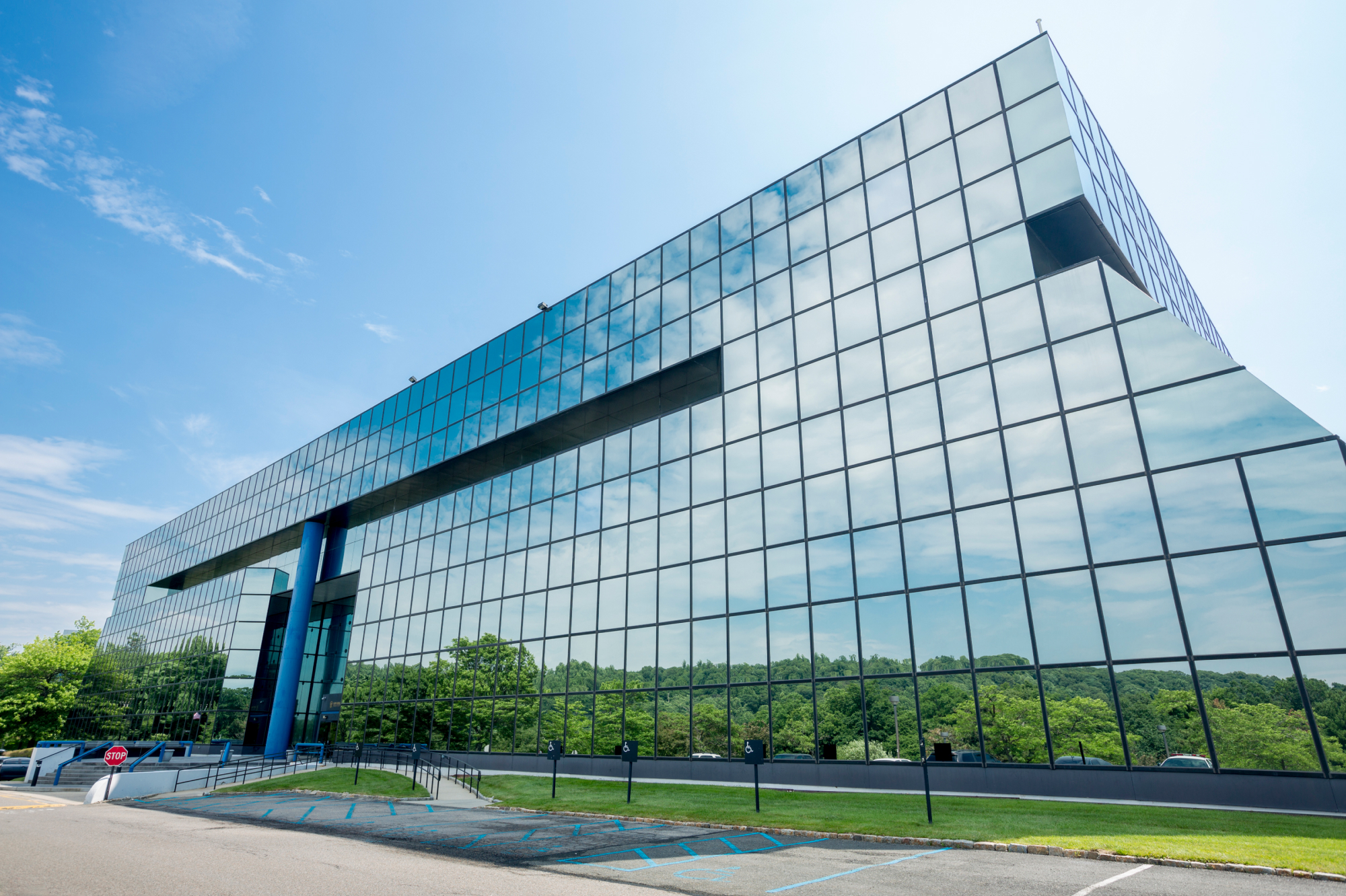 Dental building covered with windows reflecting the blue sky and green trees and foliage