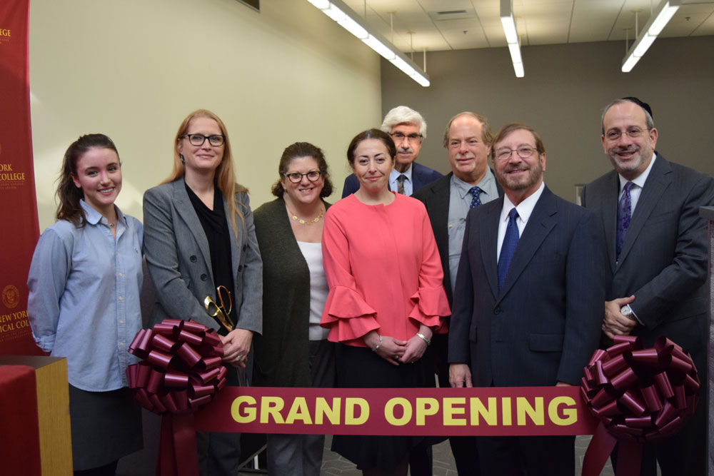 Touro and NYMC faculty smiling with grand opening banner