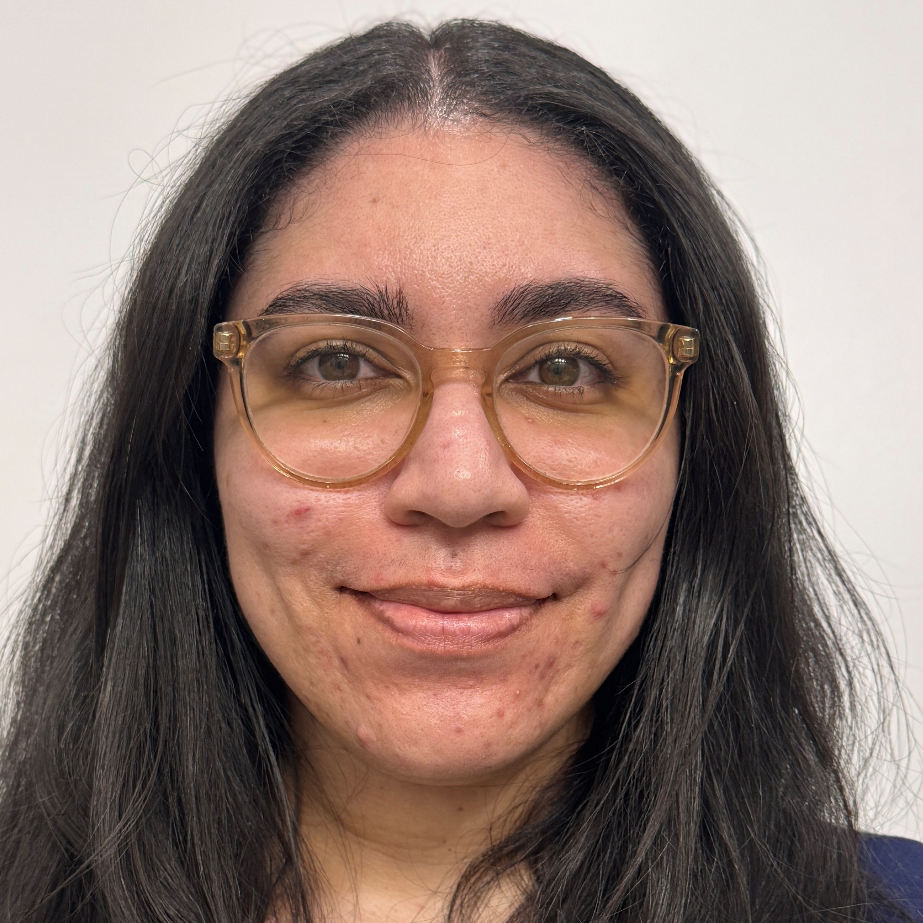 A woman with long dark brown hair and glasses smiling