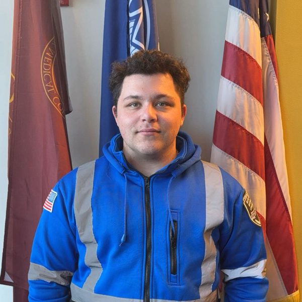 Man in blue and silver jacket in front of flags
