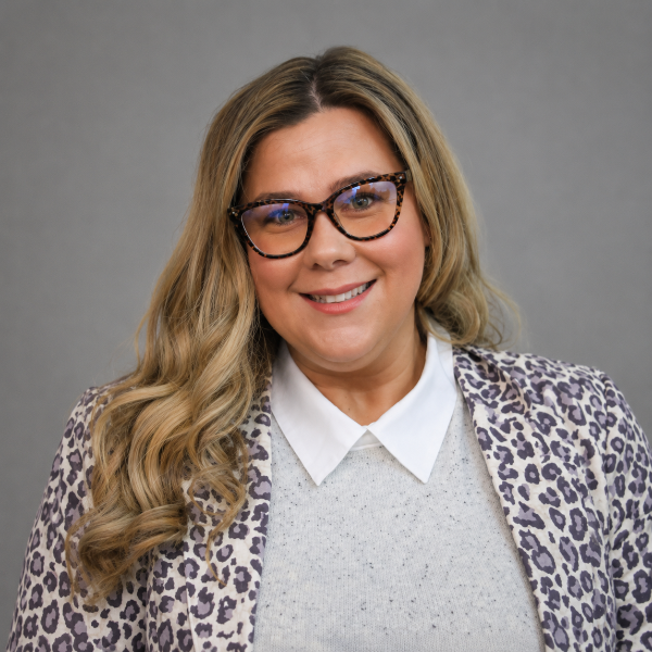 Woman in leopard print blazer with glasses smiling for headshot photo
