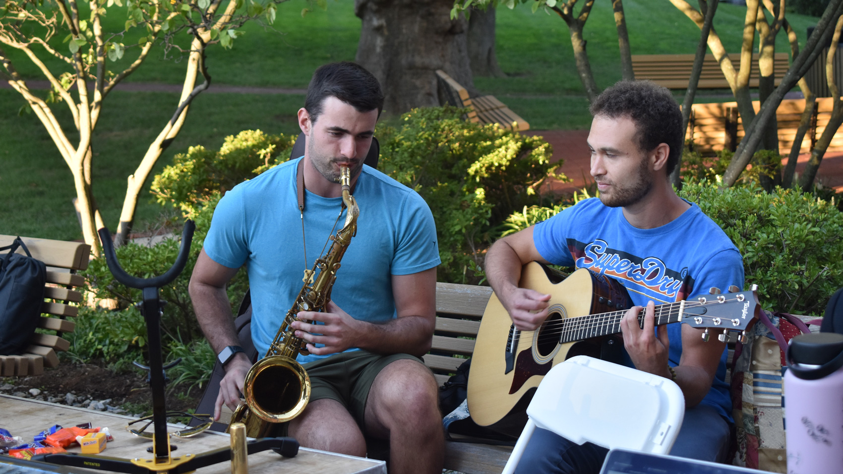 Two NYMC students playing guitar and saxophone on campus