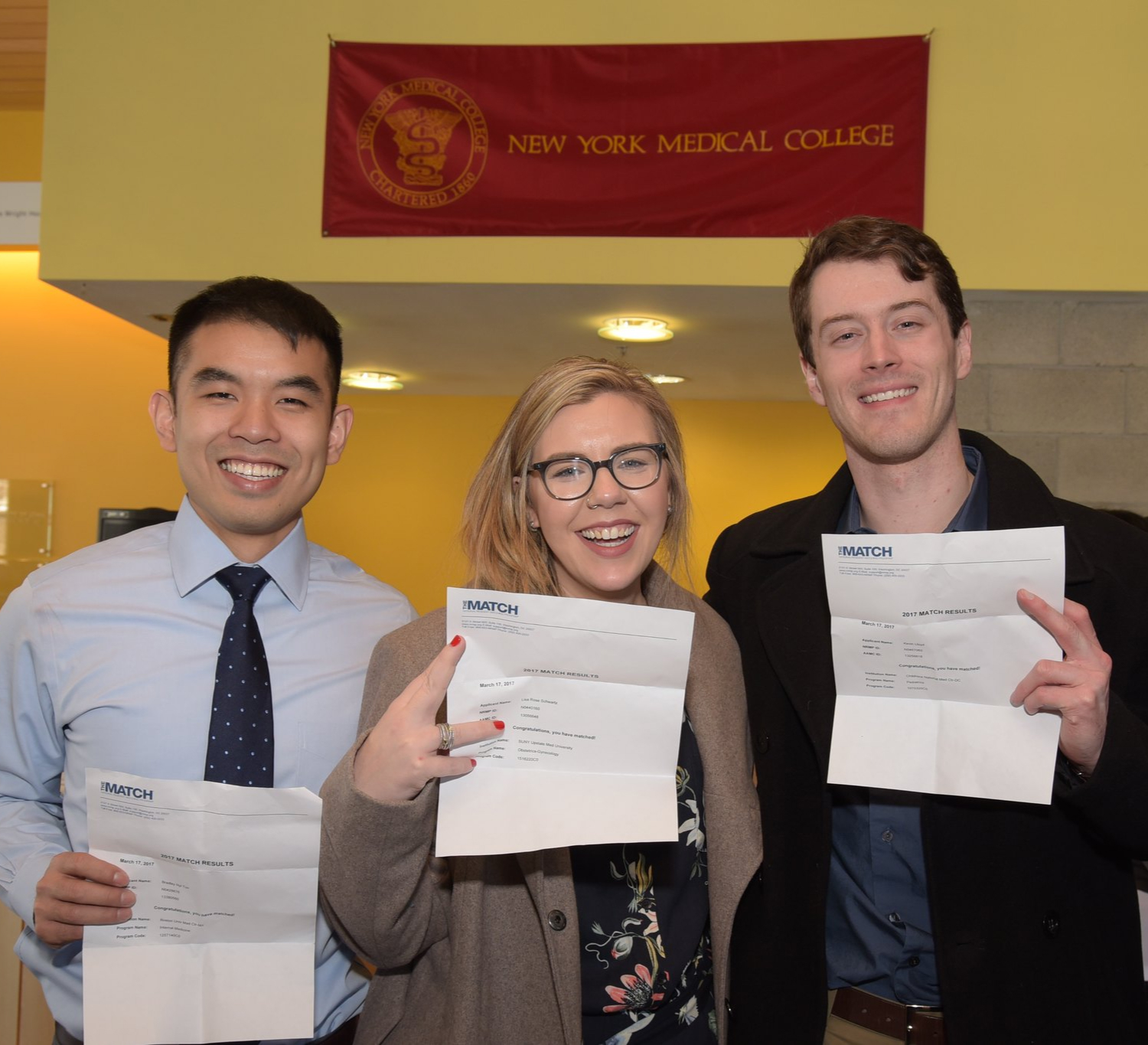 Three students proudly holding up their match day results.