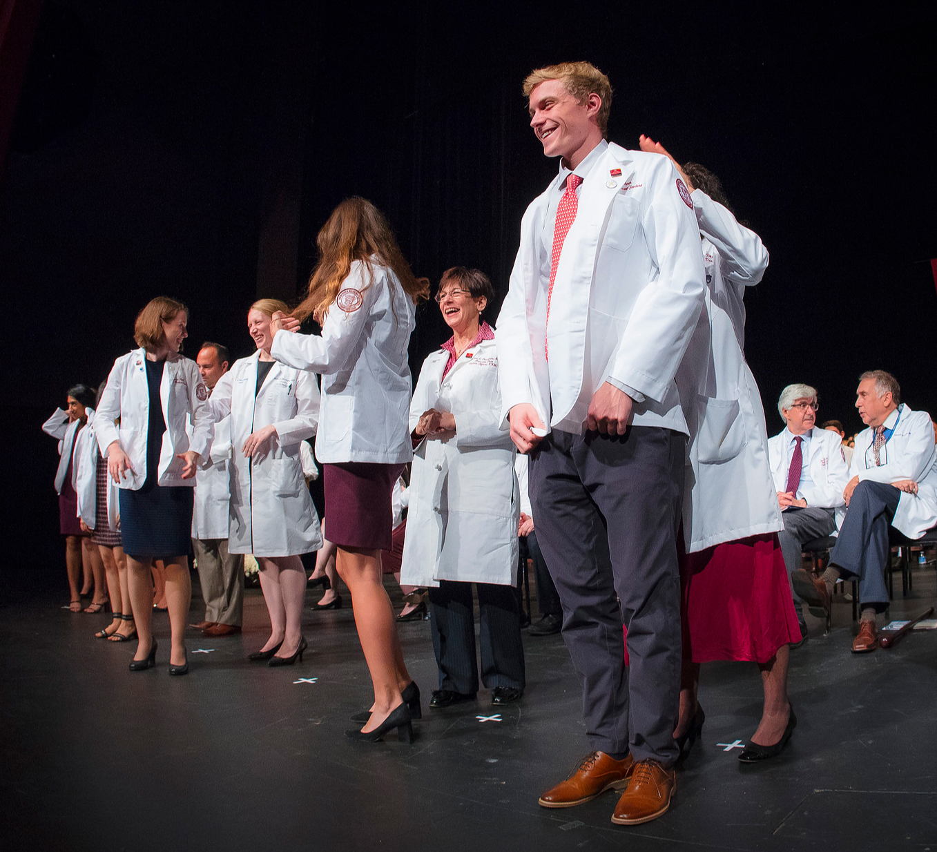 Students excitedly receiving their white coats on stage.