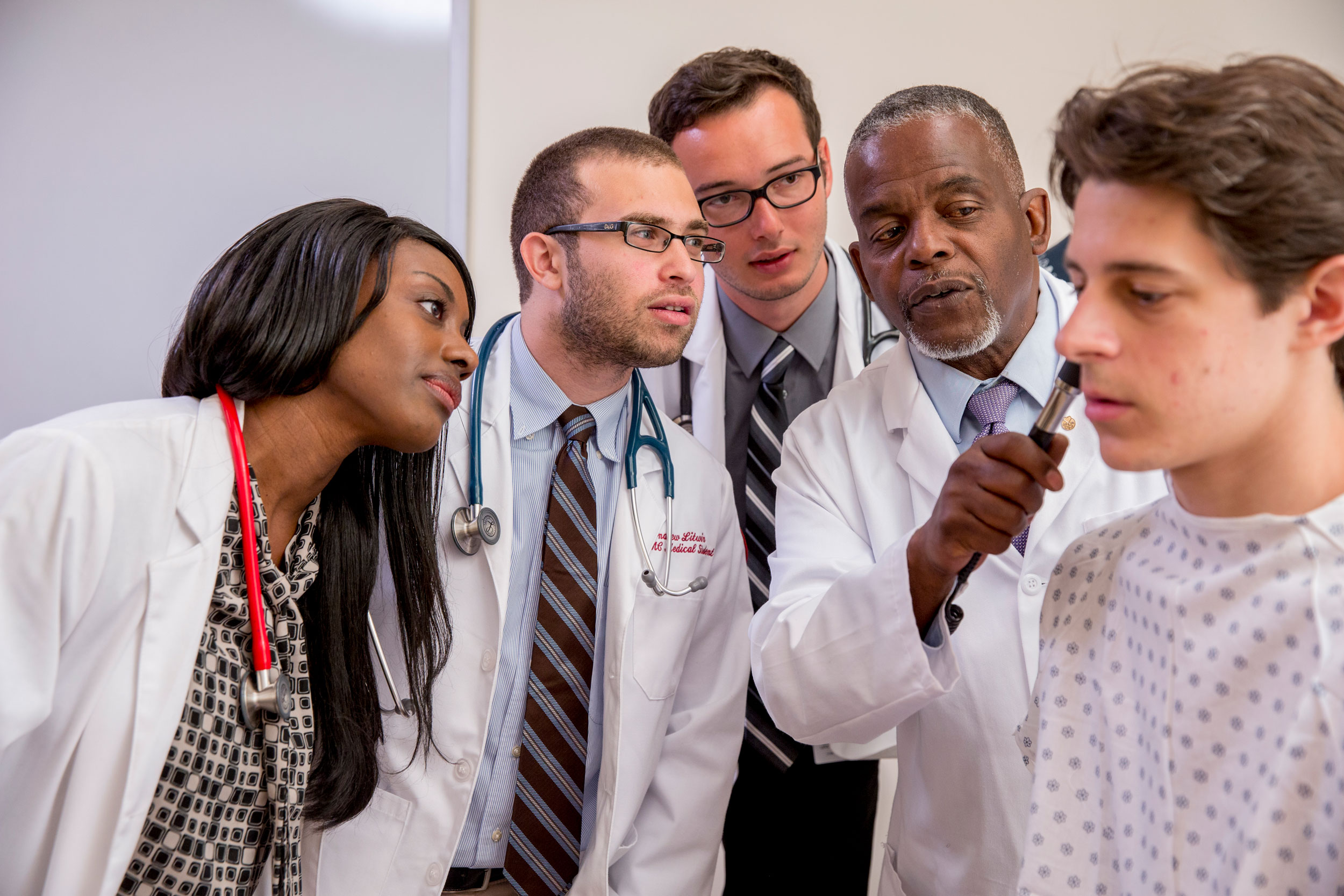 Students watch a professor look into a patient’s ear