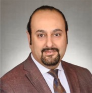 Man posing for headshot wearing brown suit blazer and tie